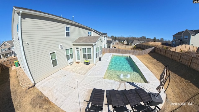 rear view of property featuring a fenced in pool and a patio area