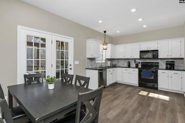 kitchen featuring tasteful backsplash, white cabinetry, sink, hanging light fixtures, and black appliances