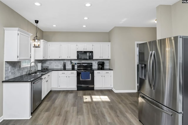 kitchen with pendant lighting, white cabinets, sink, and black appliances