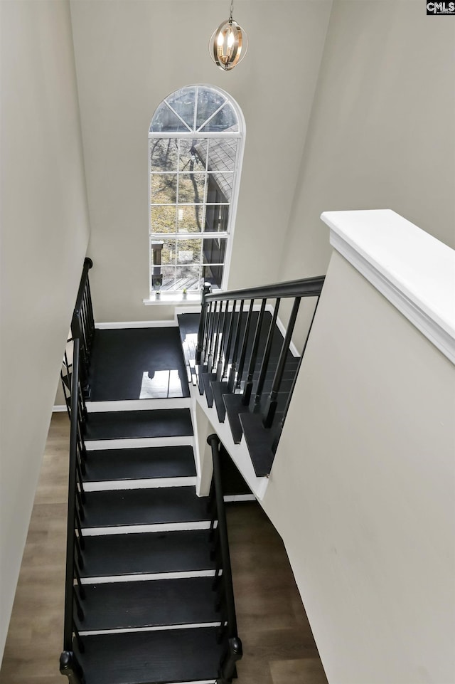 staircase with hardwood / wood-style flooring and a chandelier