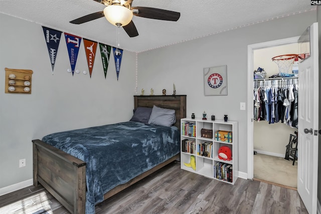 bedroom with hardwood / wood-style flooring, ceiling fan, and a textured ceiling