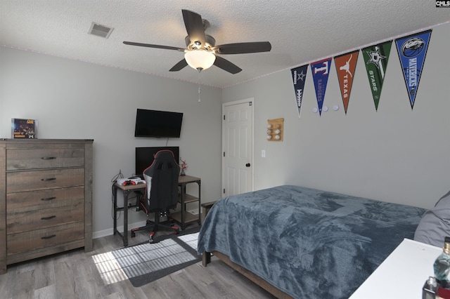 bedroom featuring ceiling fan, a textured ceiling, and light wood-type flooring