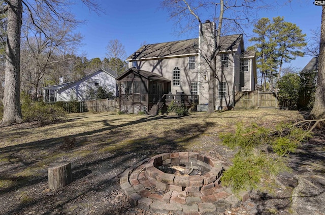 rear view of house featuring a wooden deck, an outdoor fire pit, and a sunroom