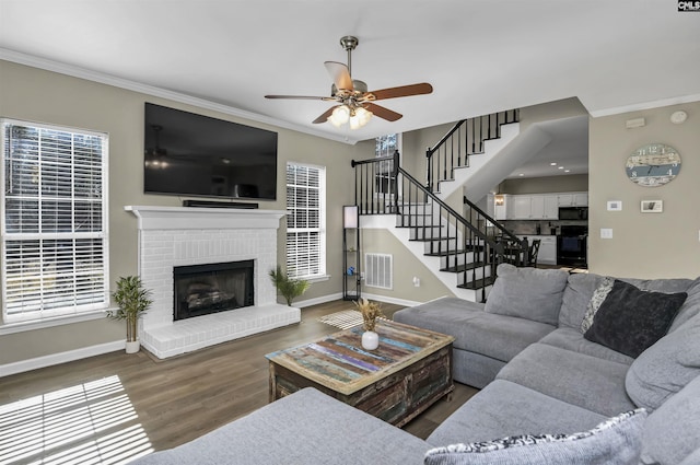 living room featuring dark hardwood / wood-style flooring, crown molding, a fireplace, and ceiling fan