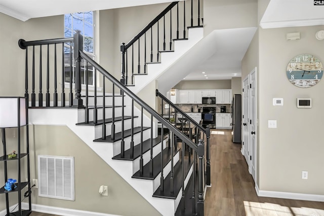 stairs with hardwood / wood-style flooring and a high ceiling