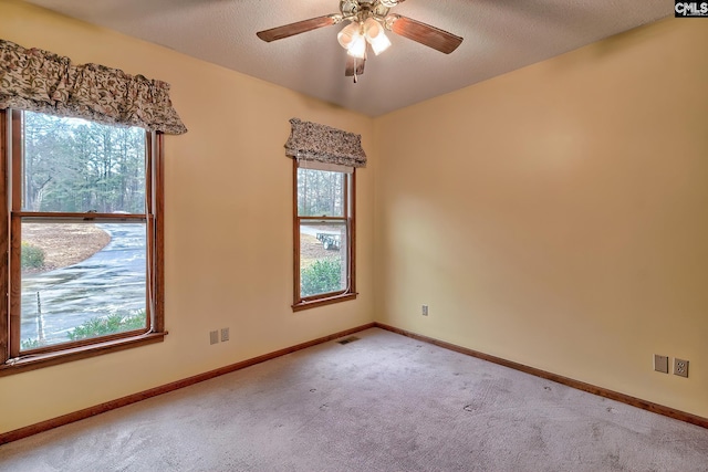 empty room with ceiling fan, light colored carpet, and a textured ceiling