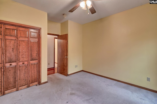 unfurnished bedroom featuring ceiling fan, light colored carpet, and a textured ceiling