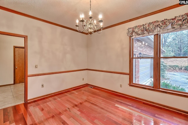 unfurnished room with hardwood / wood-style flooring, ornamental molding, a chandelier, and a textured ceiling