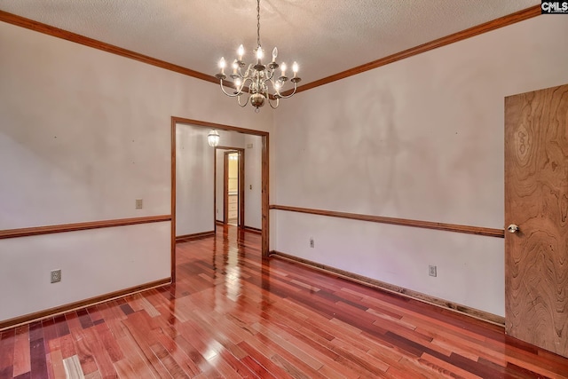 empty room featuring a notable chandelier, crown molding, wood-type flooring, and a textured ceiling