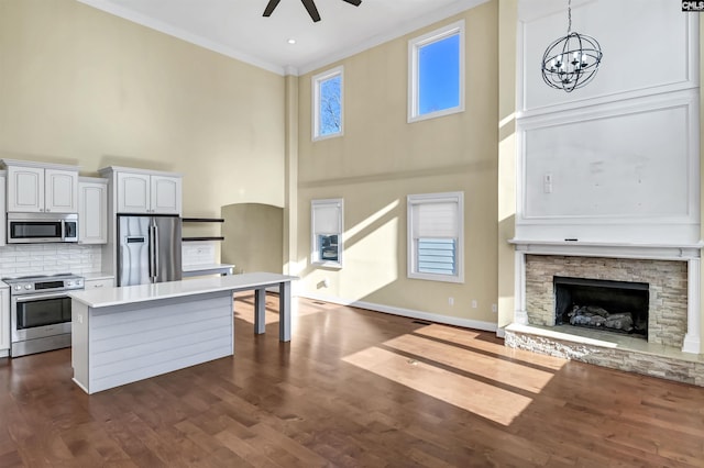 kitchen with appliances with stainless steel finishes, ceiling fan with notable chandelier, decorative light fixtures, white cabinetry, and ornamental molding