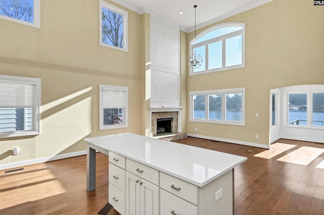 kitchen featuring dark hardwood / wood-style floors, decorative light fixtures, ornamental molding, a center island, and plenty of natural light