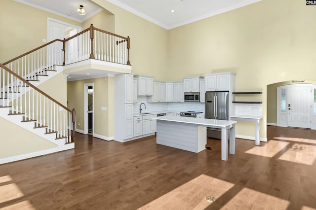 kitchen with sink, white cabinetry, crown molding, a kitchen island, and stainless steel appliances