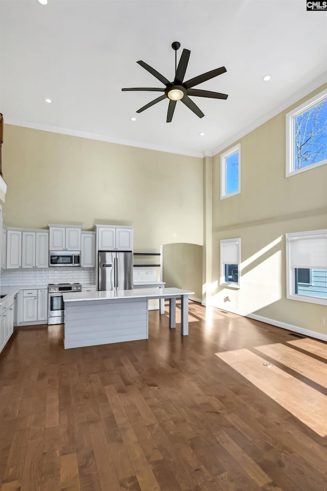 kitchen featuring ornamental molding, stainless steel appliances, dark hardwood / wood-style floors, and a kitchen island