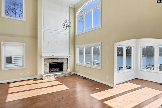 unfurnished living room with a fireplace, a chandelier, hardwood / wood-style floors, and a high ceiling