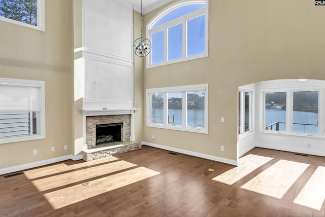 unfurnished living room featuring hardwood / wood-style flooring, a high ceiling, a fireplace, and an inviting chandelier