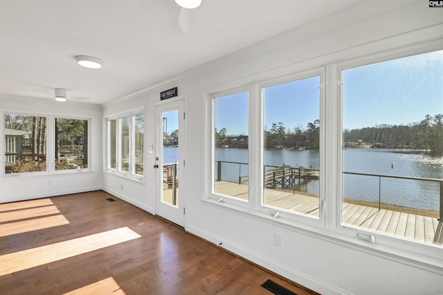 unfurnished sunroom with a water view and ceiling fan