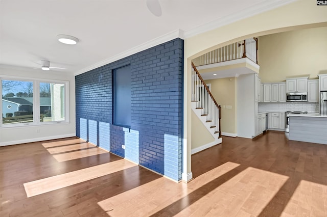 interior space with hardwood / wood-style flooring, ornamental molding, brick wall, and ceiling fan