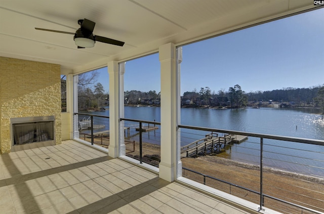 wooden terrace with a fireplace, ceiling fan, and a water view