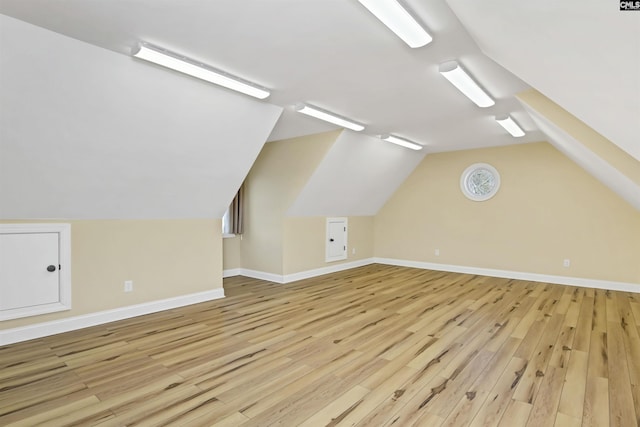 additional living space featuring vaulted ceiling and light hardwood / wood-style floors