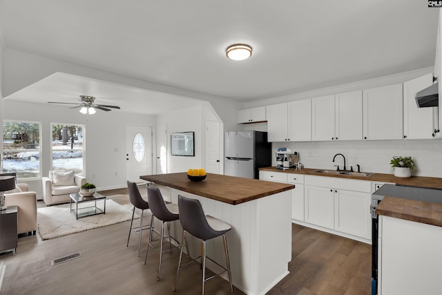 kitchen featuring sink, a breakfast bar, appliances with stainless steel finishes, butcher block counters, and white cabinets