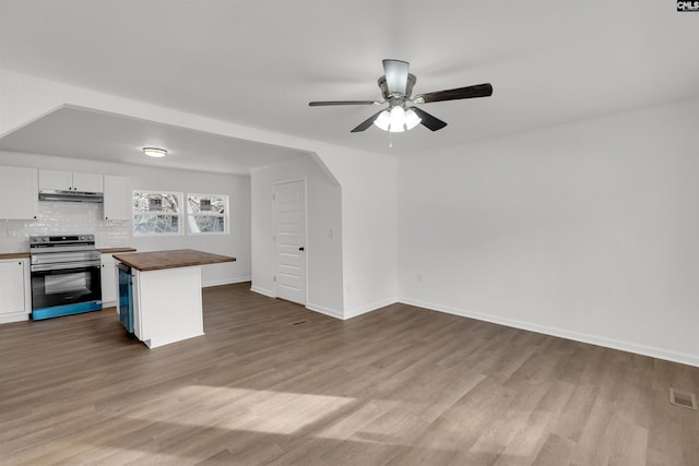 kitchen with butcher block countertops, appliances with stainless steel finishes, white cabinetry, hardwood / wood-style floors, and decorative backsplash