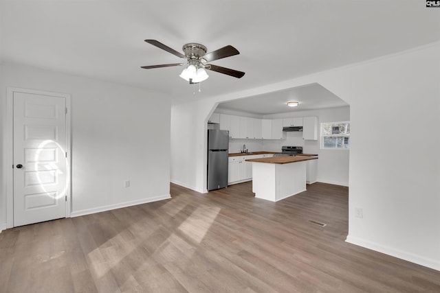 kitchen with stainless steel appliances, hardwood / wood-style flooring, white cabinets, and wood counters