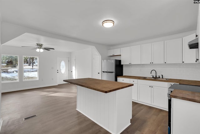 kitchen with white cabinets, sink, stainless steel fridge, and wood counters