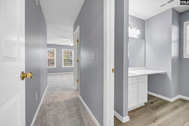 hallway featuring light colored carpet and a textured ceiling