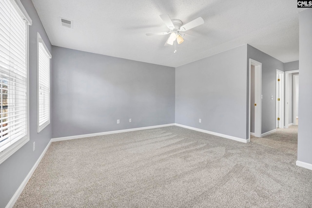 carpeted empty room featuring ceiling fan, a healthy amount of sunlight, and a textured ceiling