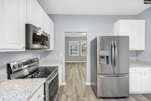 kitchen featuring stainless steel appliances, light stone countertops, light wood-type flooring, and white cabinets