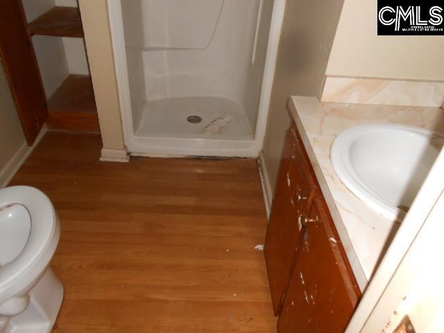 bathroom featuring vanity, hardwood / wood-style flooring, toilet, and a shower