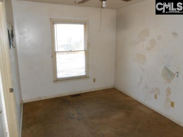 unfurnished room with ceiling fan and concrete flooring