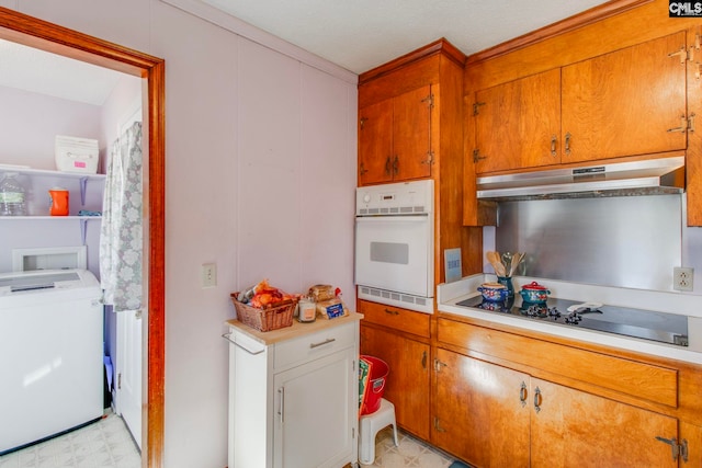 kitchen with black electric stovetop, oven, and washer / dryer