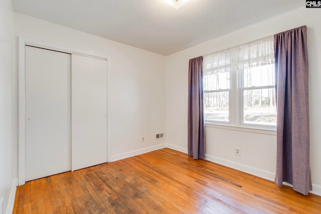 unfurnished bedroom with hardwood / wood-style flooring, a textured ceiling, and a closet