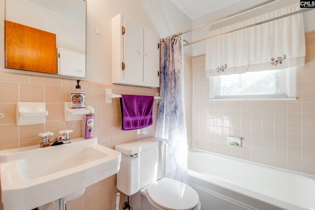 full bathroom with shower / bathtub combination with curtain, sink, toilet, and tile walls