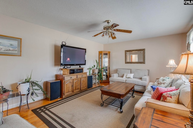 living room with a textured ceiling, ceiling fan, and light wood-type flooring