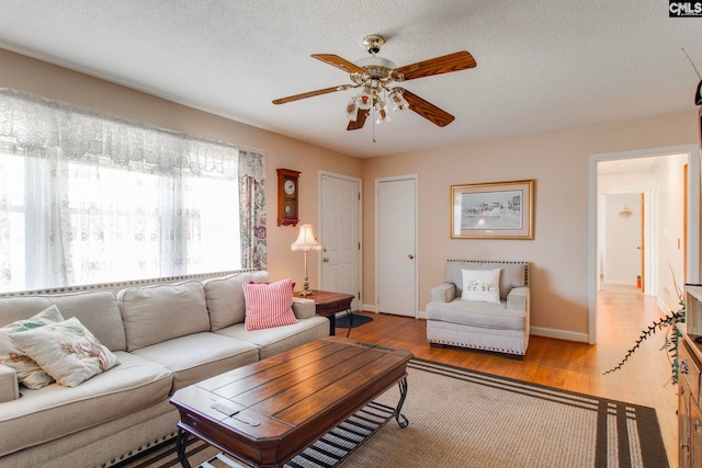 living room with wood-type flooring, ceiling fan, and a textured ceiling