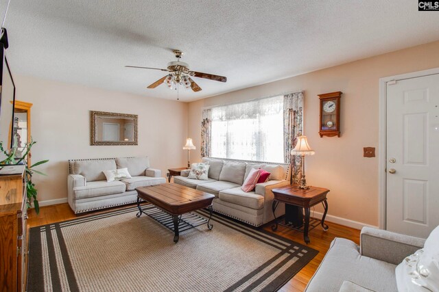 living room featuring ceiling fan, hardwood / wood-style floors, and a textured ceiling