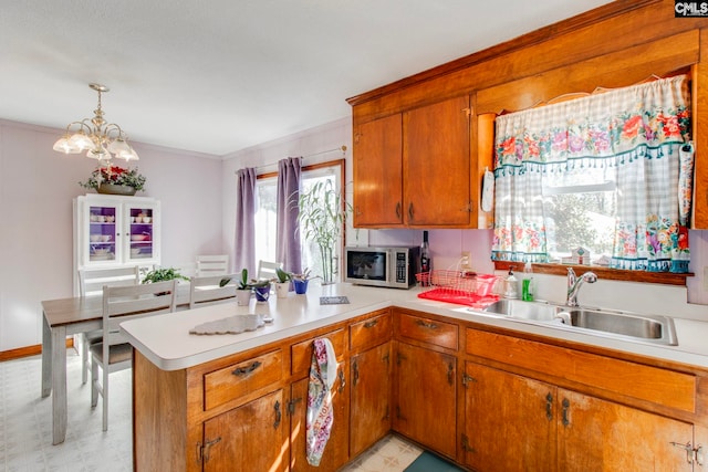 kitchen featuring sink, crown molding, decorative light fixtures, kitchen peninsula, and a notable chandelier