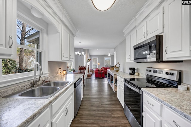 kitchen with white cabinetry, stainless steel appliances, sink, and hanging light fixtures