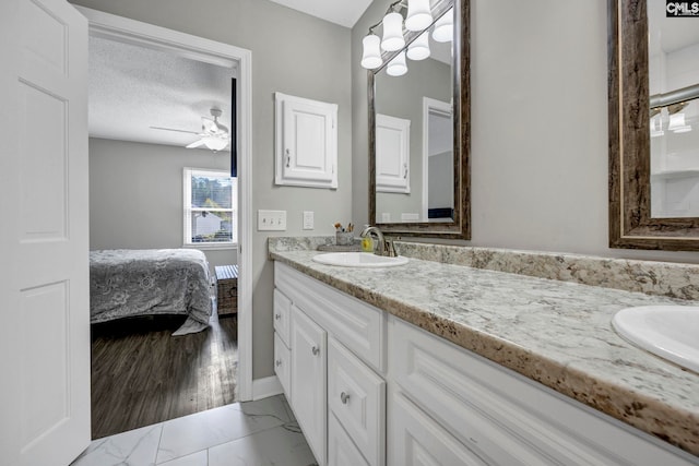 bathroom featuring ceiling fan, vanity, and a textured ceiling