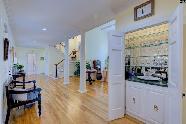 bar featuring white cabinetry, ornamental molding, light hardwood / wood-style floors, and ornate columns