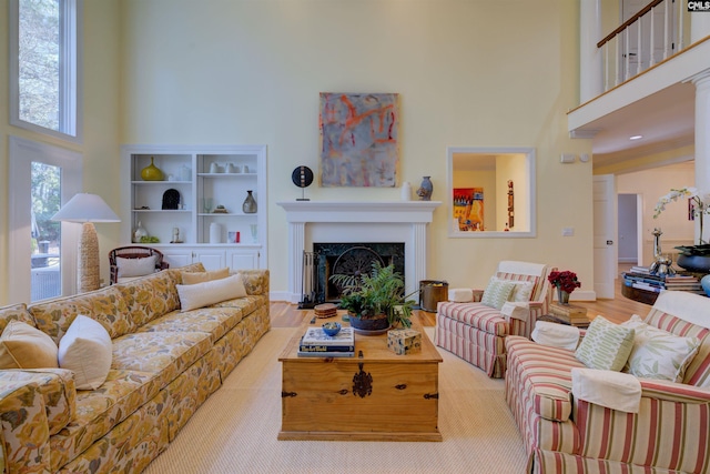 living room with a towering ceiling, a premium fireplace, and light hardwood / wood-style floors