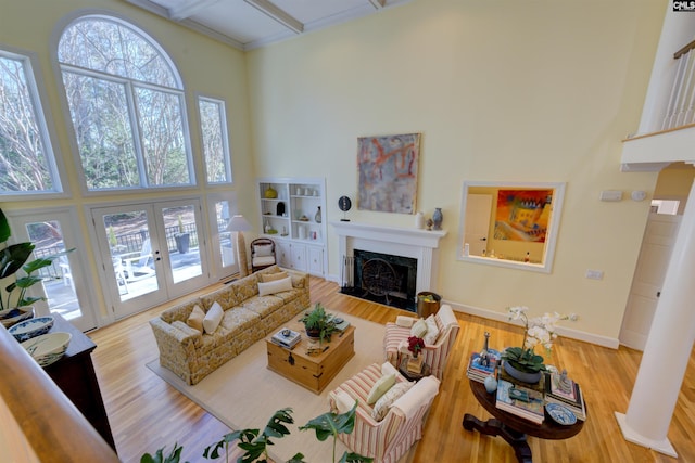 living room featuring a towering ceiling, light hardwood / wood-style floors, and french doors