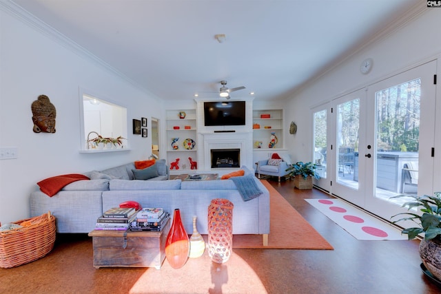 living room featuring built in shelves, french doors, ornamental molding, ceiling fan, and a fireplace