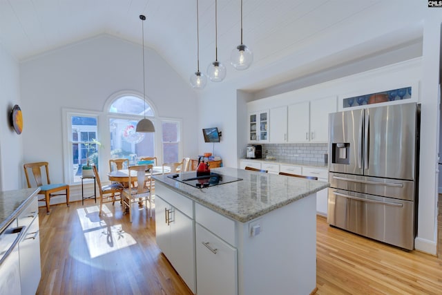 kitchen featuring black electric cooktop, stainless steel fridge, a kitchen island, and white cabinets