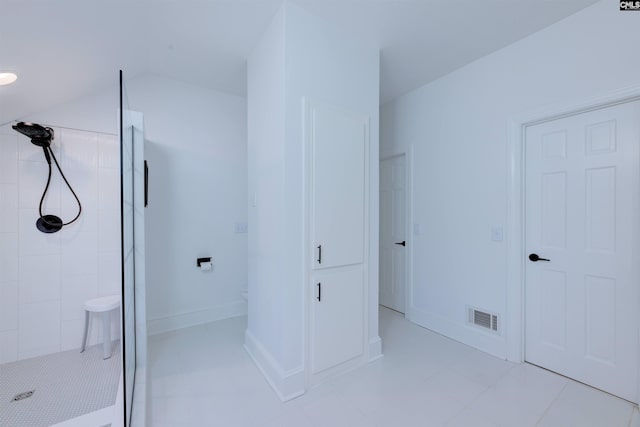 bathroom featuring lofted ceiling and tiled shower