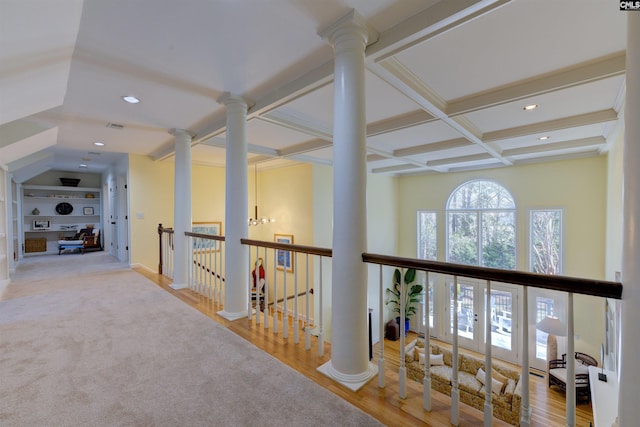 corridor with built in shelves, coffered ceiling, decorative columns, beam ceiling, and hardwood / wood-style floors