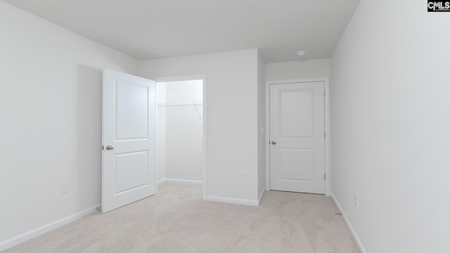 unfurnished bedroom featuring light carpet and a closet