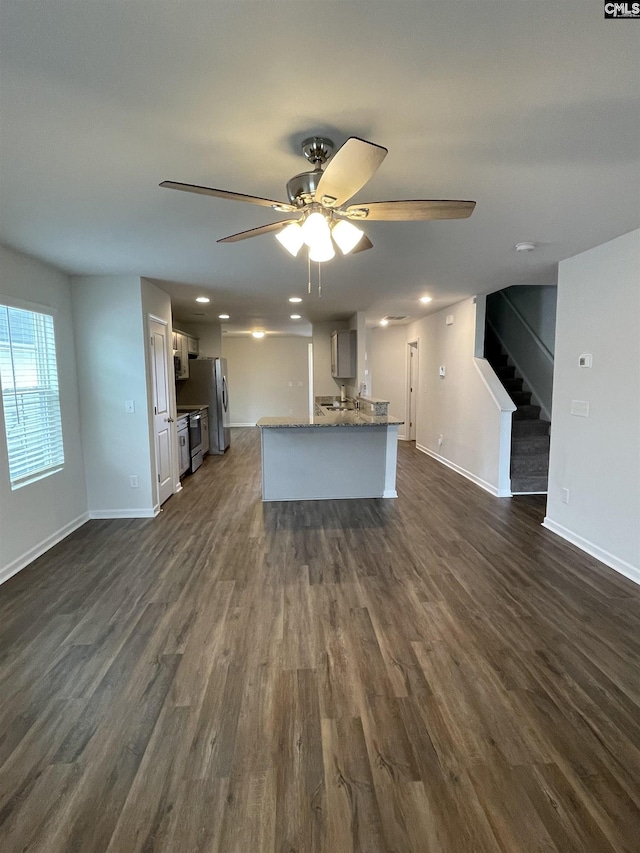 unfurnished living room with dark hardwood / wood-style floors and ceiling fan